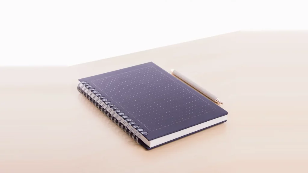 Navy dotted notebook with a pencil on a wooden desk